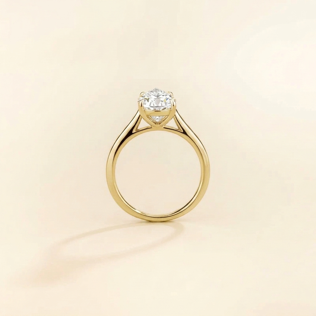 Solitaire engagement ring with a 2 carat pear-cut diamond in a three-prong cathedral setting on a slim polished yellow gold band.