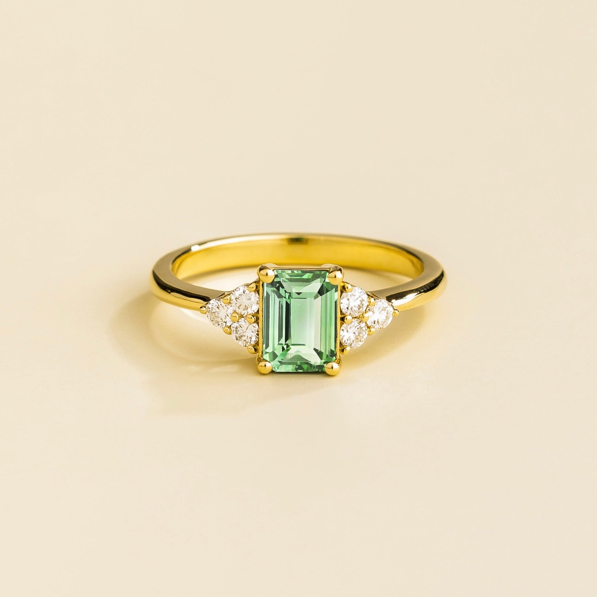 Juvetti yellow gold ring featuring an emerald-cut lab-grown green sapphire with lab-grown diamond side stones.