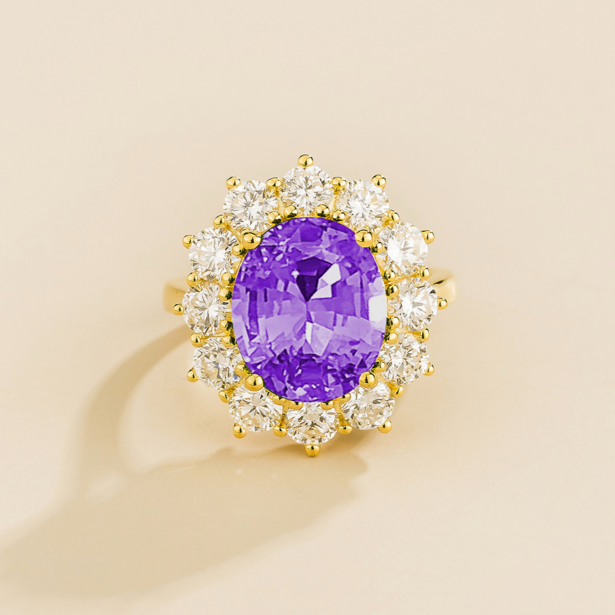 Juvetti yellow gold halo ring featuring an oval lab-grown purple sapphire surrounded by round lab-grown diamonds.