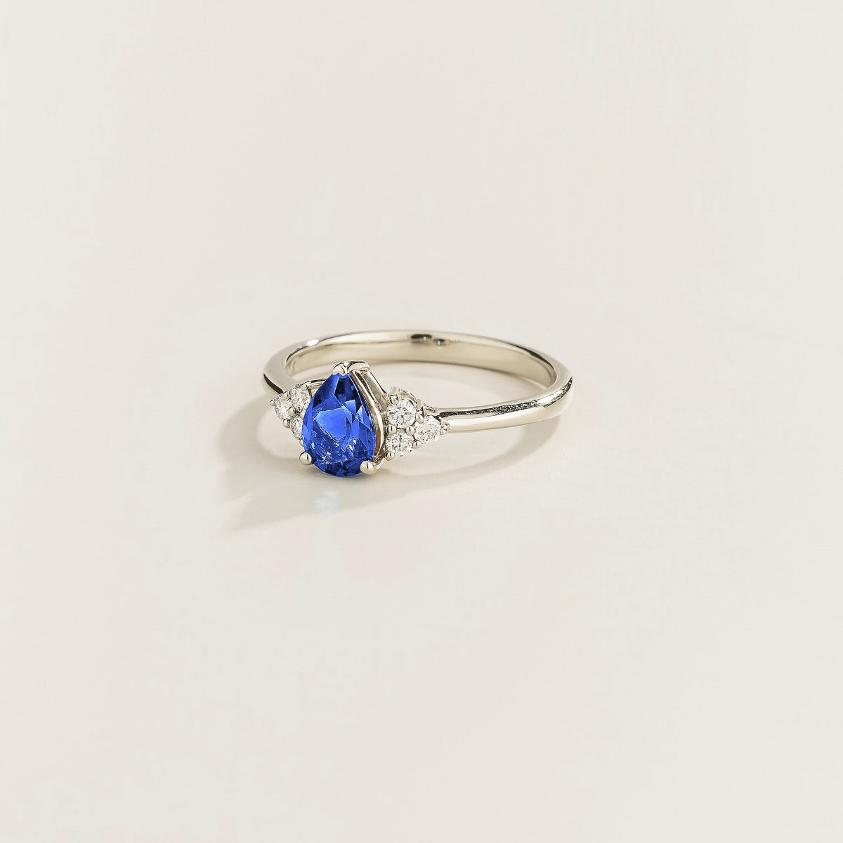 Juvetti white gold ring featuring a pear-cut lab-grown royal blue sapphire with lab-grown diamond side stones.