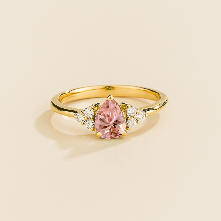 Juvetti yellow gold ring featuring a pear-cut lab-grown morganite with lab-grown diamond side stones.