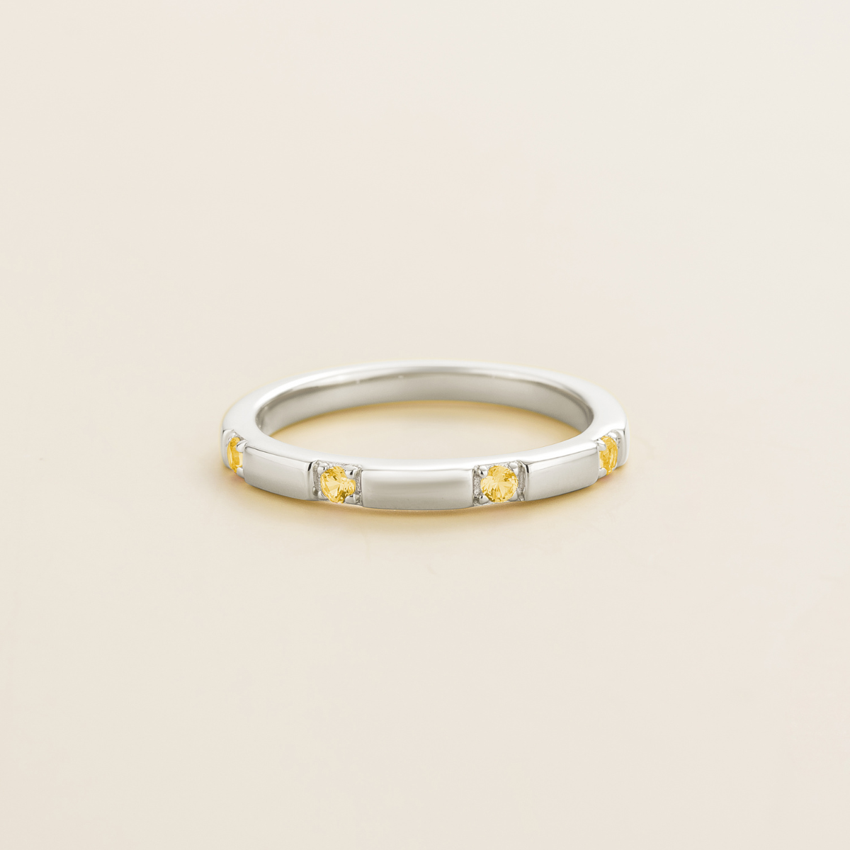 Juvetti white gold band set with round lab-grown yellow sapphire gemstones in a sleek modern design.
