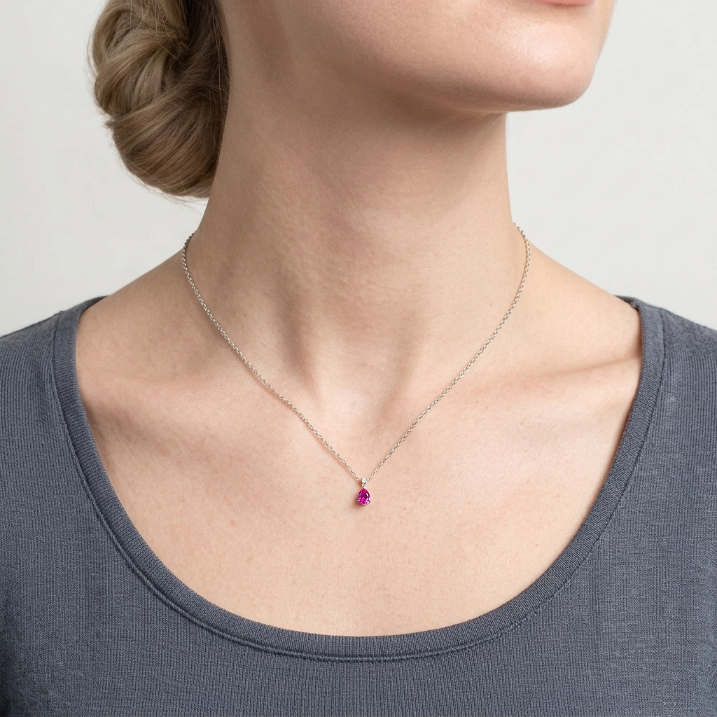 A model is wearing Ori Vivid Pink Sapphire & Diamond Pear Drop Pendant Necklace in White Gold set with lab grown diamond and pear cut vivid pink sapphire gem stones.

