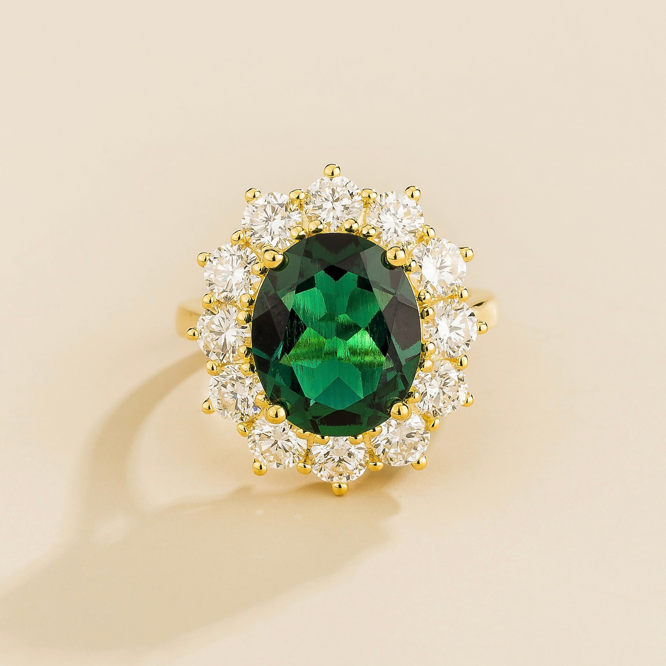 A gold ring featuring an oval emerald centerpiece surrounded by a halo of round diamonds.