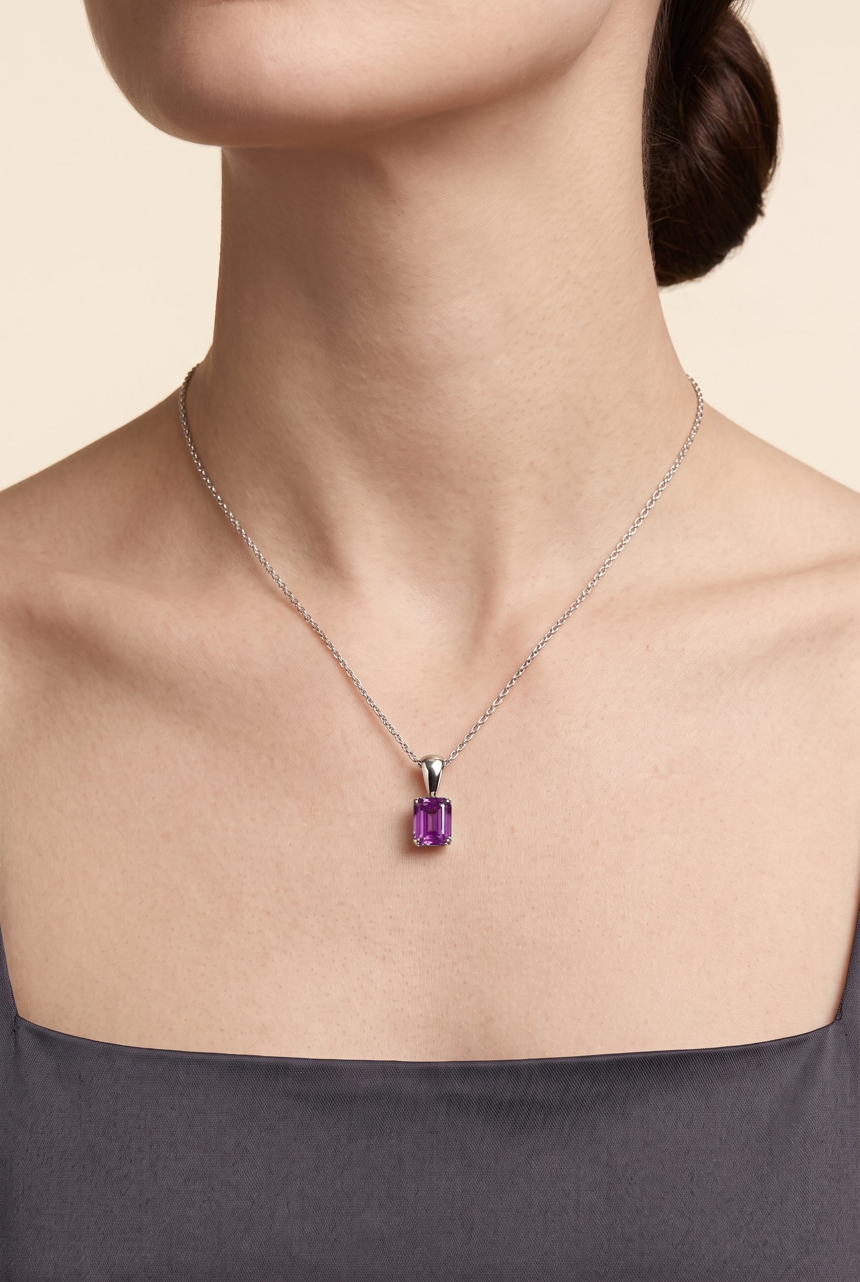 A model is wearing Thamani Necklace in White gold set with Emerald cut Purple Sapphire gemstones.
