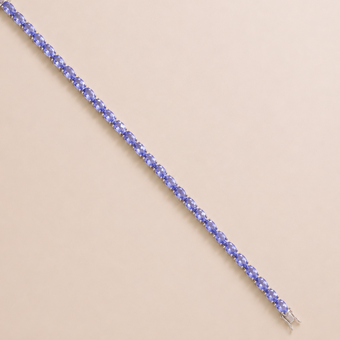 A white gold tennis bracelet set with oval light blue sapphire gemstones.