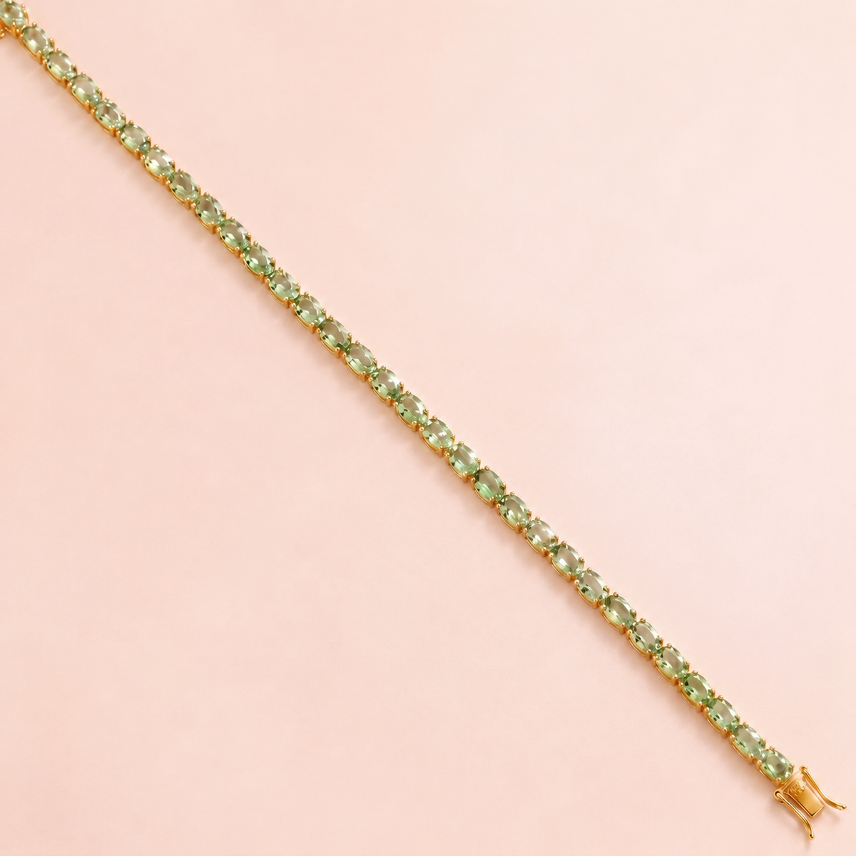 A gold tennis bracelet set with oval green sapphire gemstones.