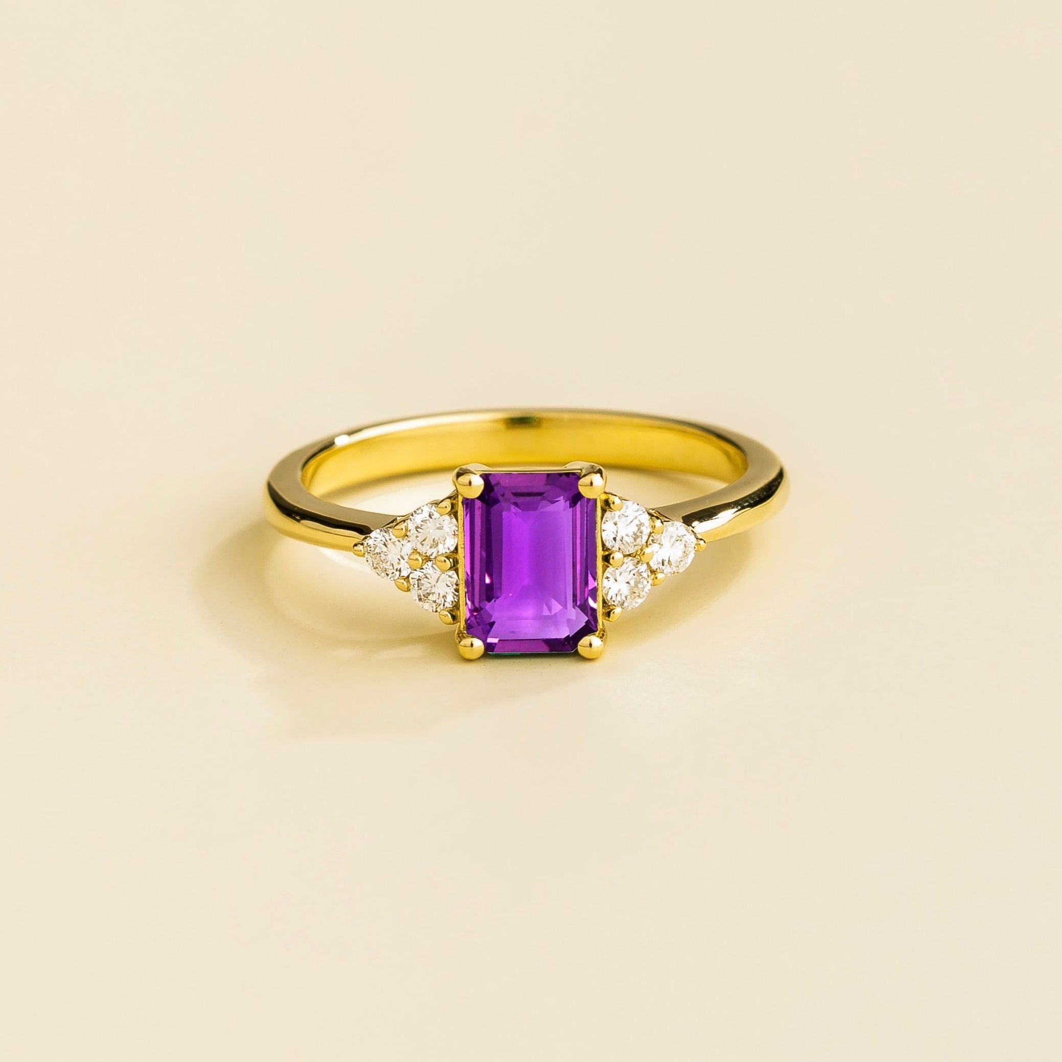Juvetti yellow gold ring featuring an emerald-cut lab-grown purple sapphire with lab-grown diamond side stones.