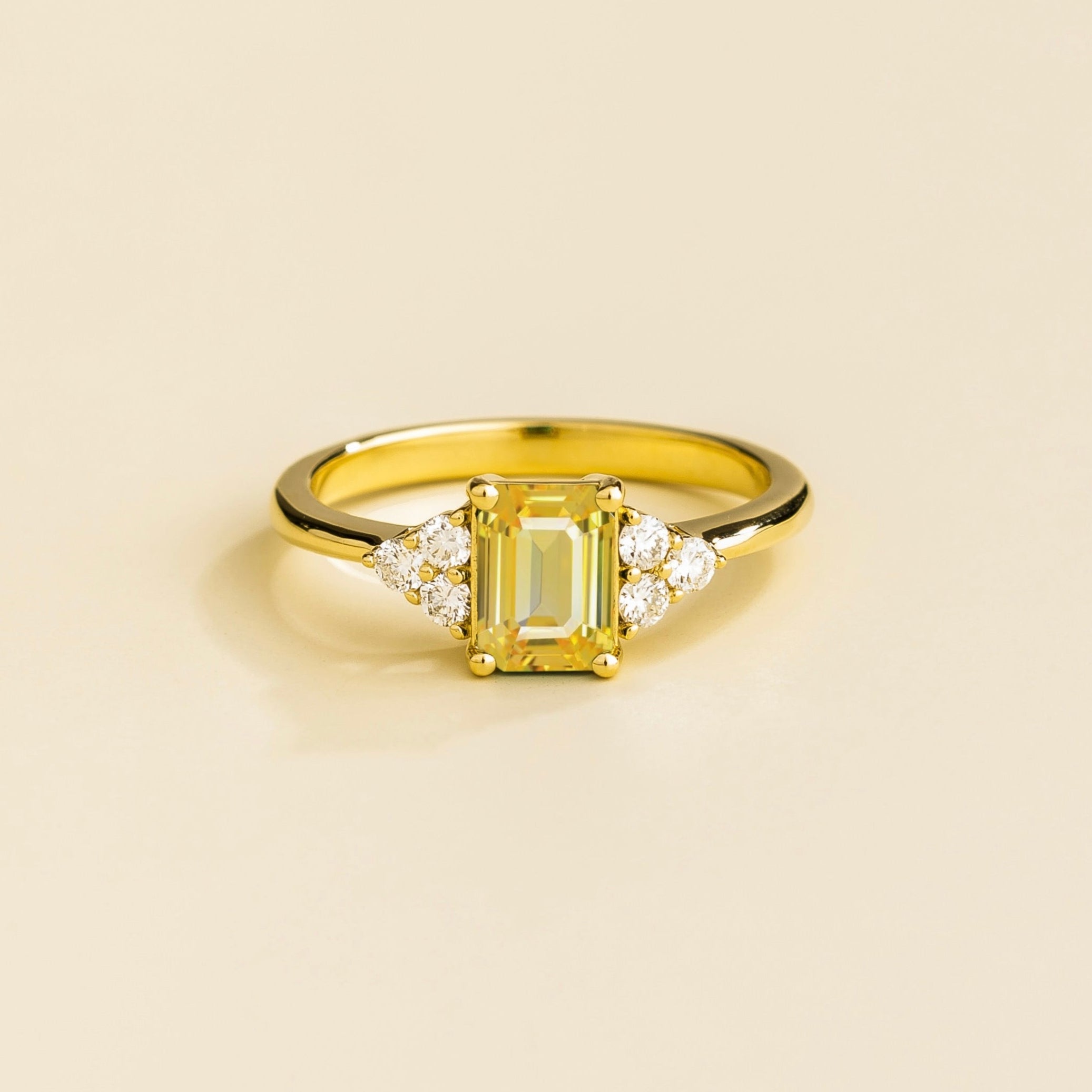 Juvetti yellow gold ring featuring an emerald-cut lab-grown yellow sapphire with lab-grown diamond side stones.