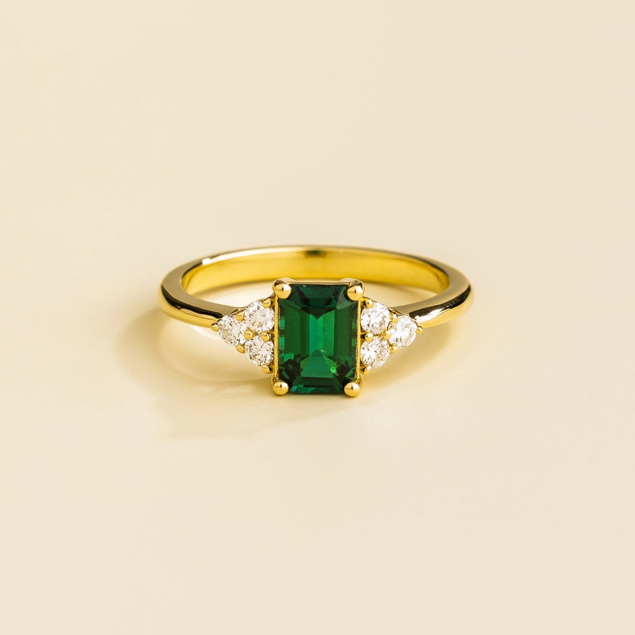 Juvetti yellow gold ring featuring an emerald-cut lab-grown emerald with lab-grown diamond side stones.
