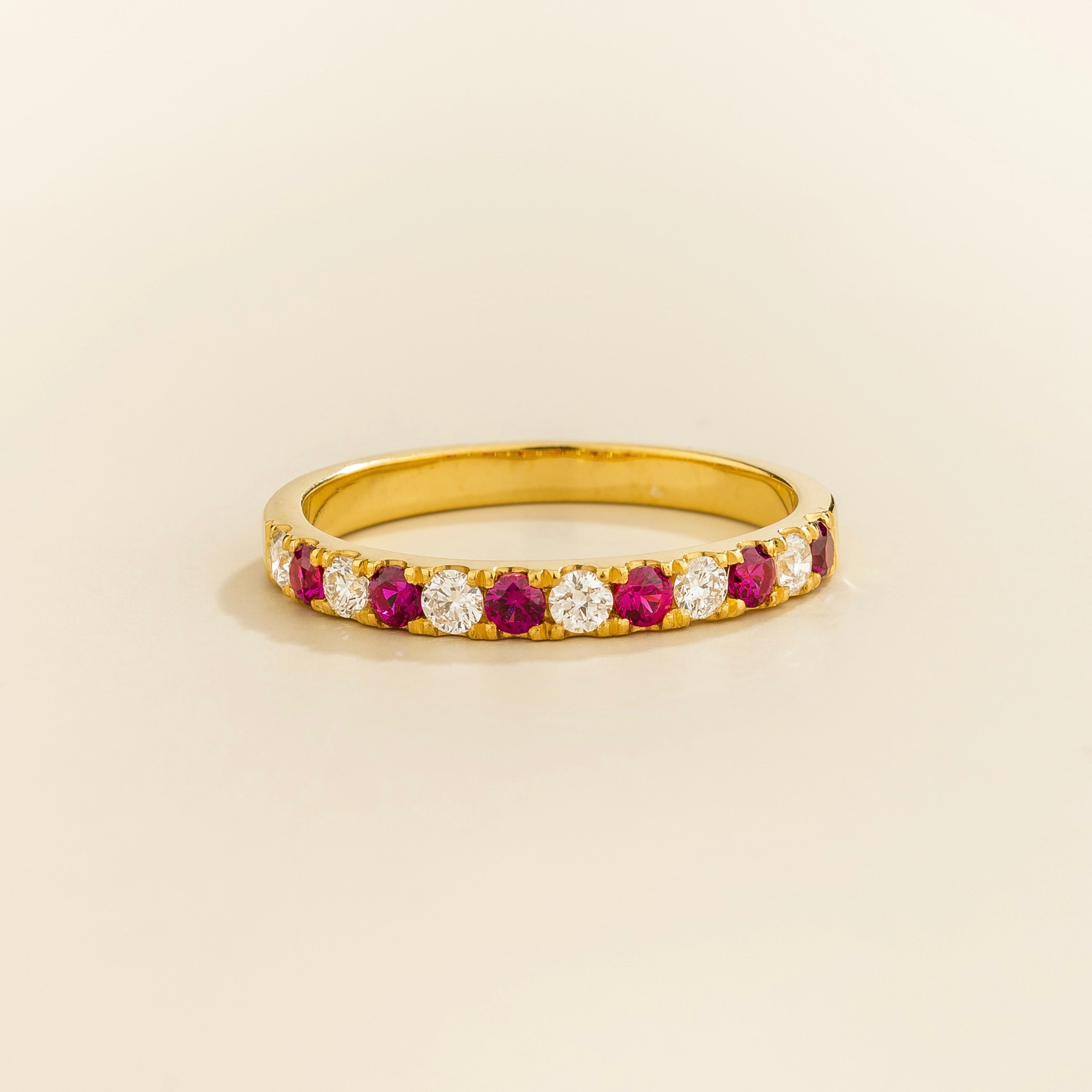 A gold half eternity ring with alternating ruby and diamond gemstones
