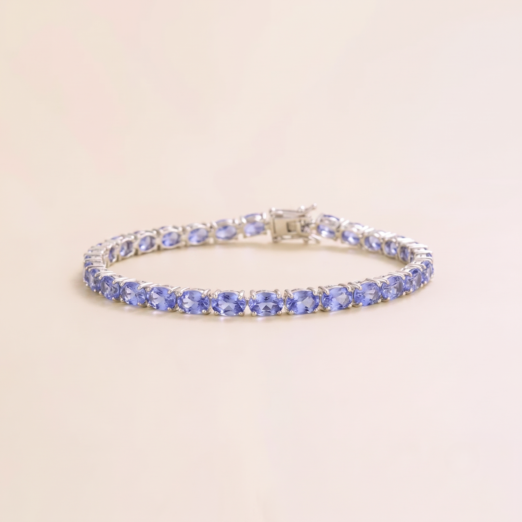A white gold tennis bracelet set with oval light blue sapphire gemstones.