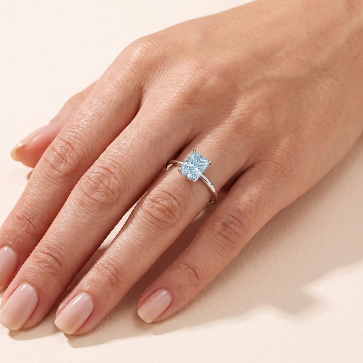 A model is wearing The Clair Radiant Shape Aquamarine Cathedral Solitaire Ring.