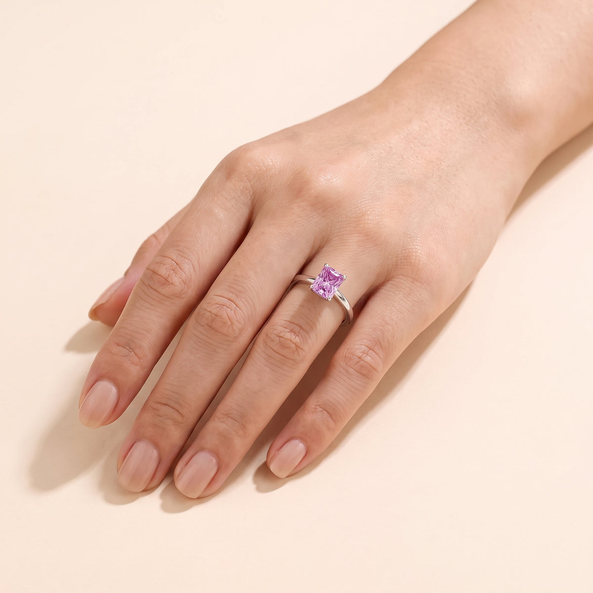 A model is wearing The Clair Radiant Shape Purple Sapphire Cathedral Solitaire Ring