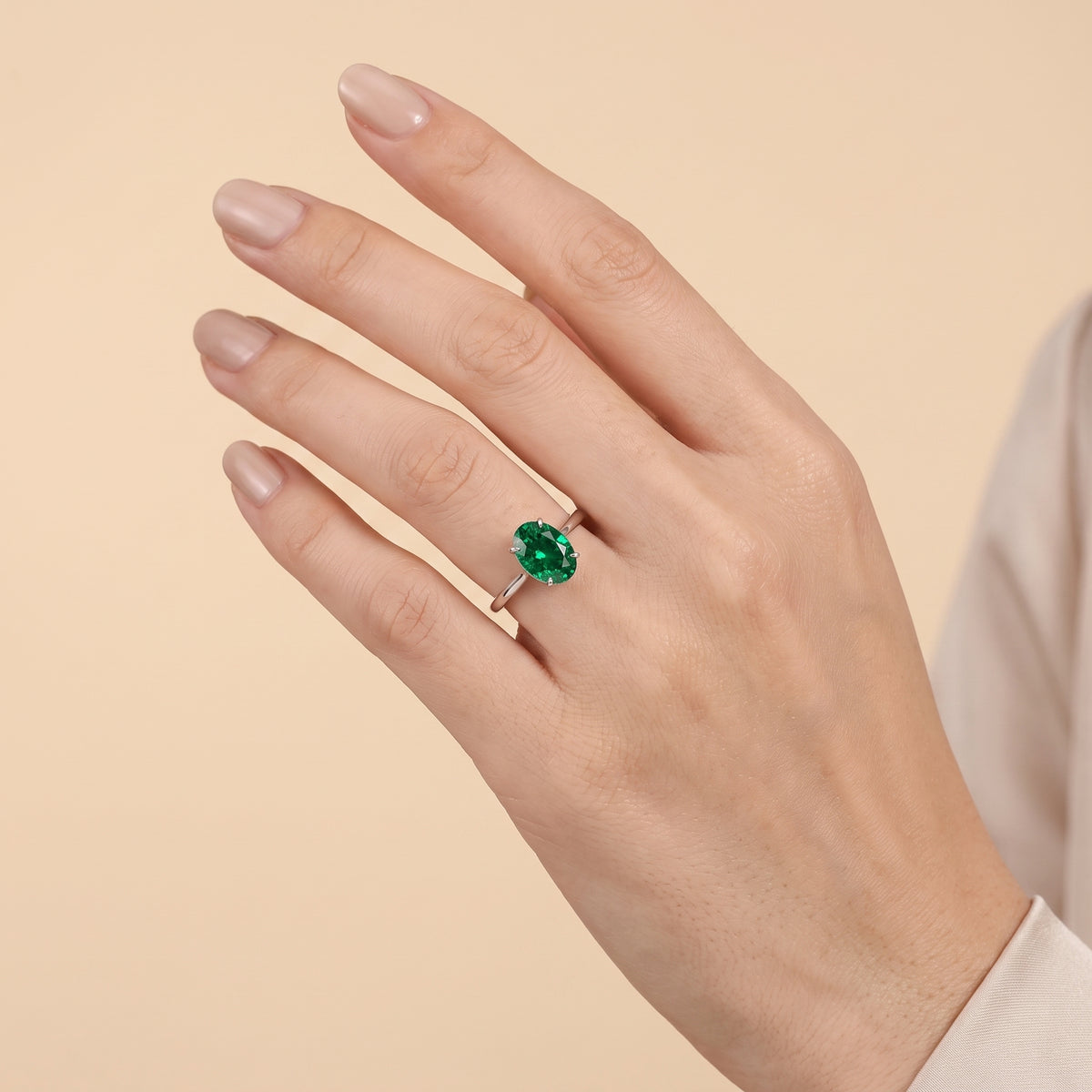The model is wearing Lyra Oval Shape Emerald Cathedral Solitaire Ring in White Gold