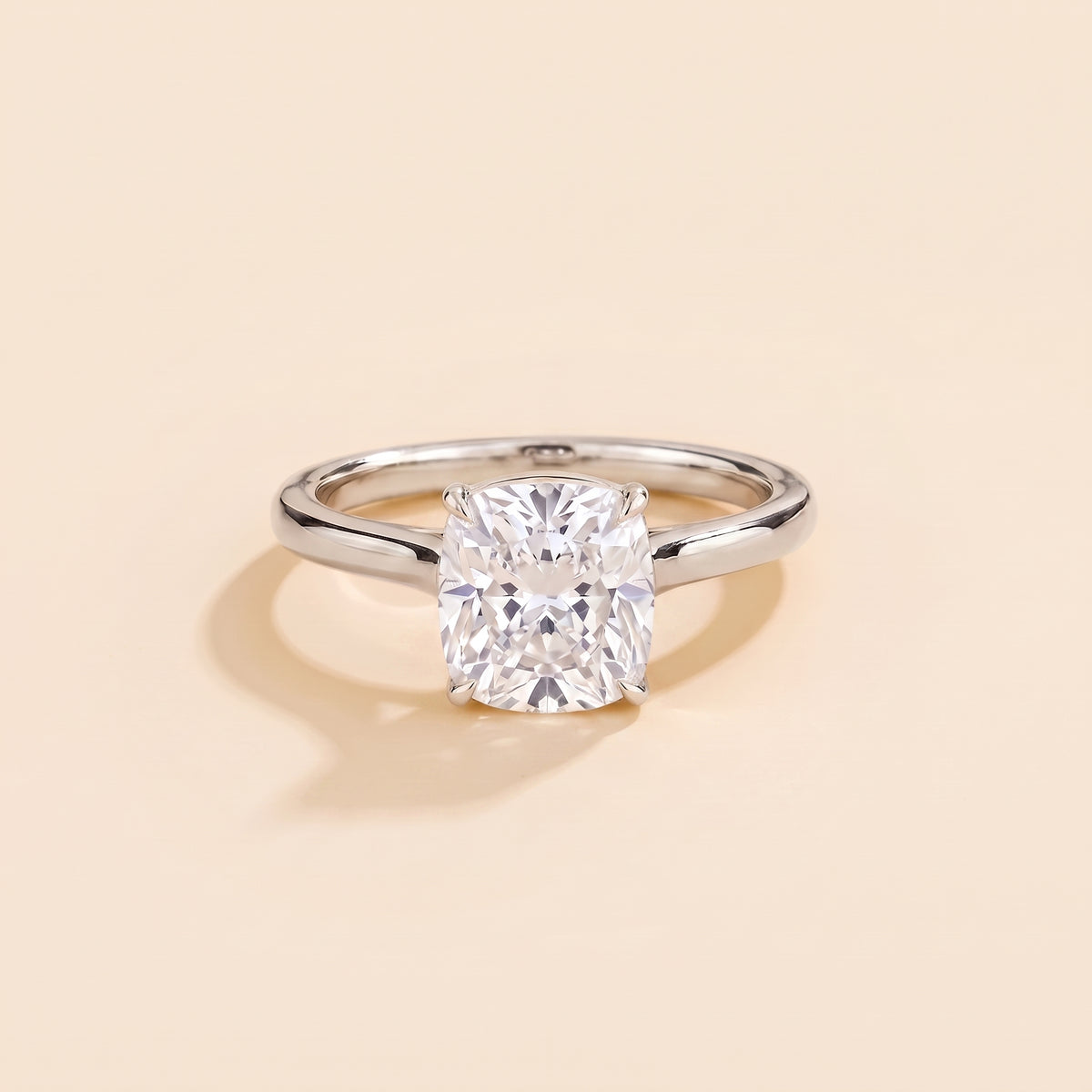 Solitaire engagement ring with a 2 carat cushion-cut diamond in a four-prong cathedral setting on a slim polished white-metal band.