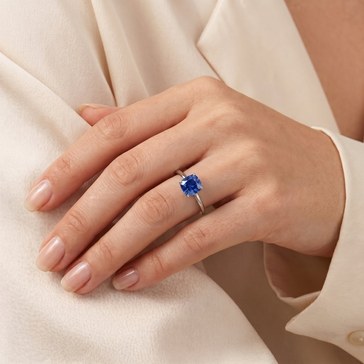 A model is wearing Iris Cushion Shape Blue Sapphire Cathedral Solitaire 