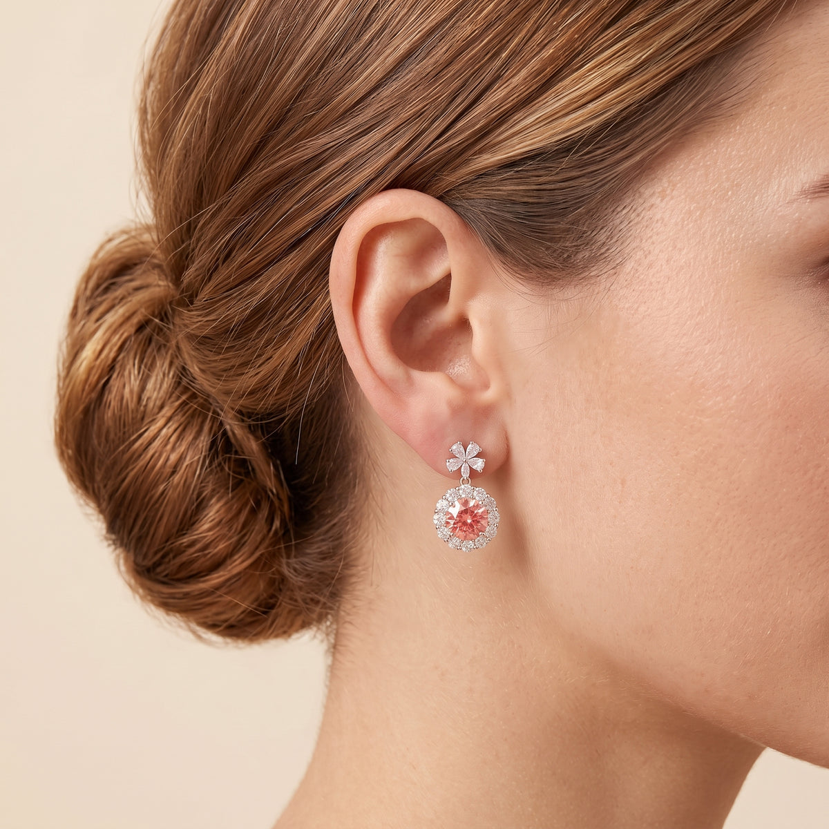 A Model is wearing The Antoinette Round Padparadscha Sapphire & Diamond Halo Pendant Earrings with Flower Bail