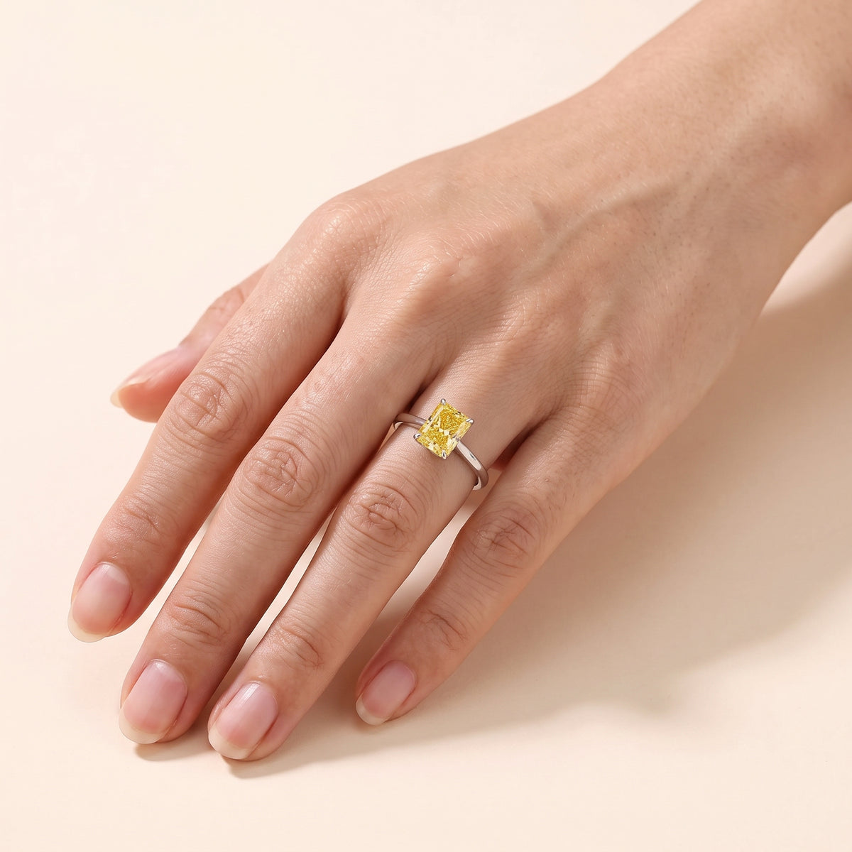 A model is wearing The Clair Radiant Shape Yellow Saphire Cathedral Solitaire Ring