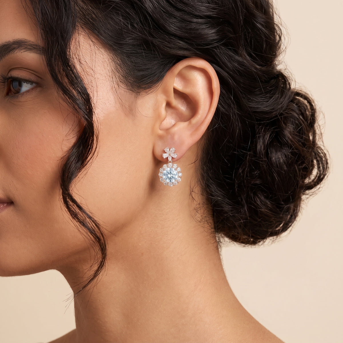 A model is wearing The Antoinette Round Aquamarine & Diamond Halo Pendant Earrings with Flower Bail 