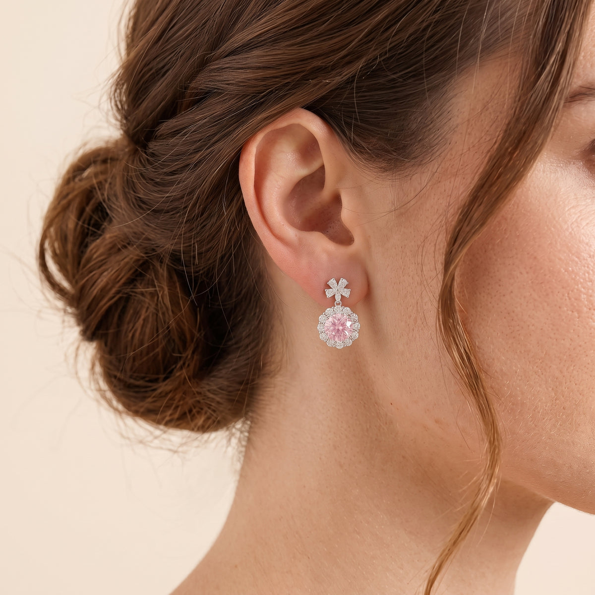 A model is wearing The Antoinette Round Pastel Pink Sapphire & Diamond Halo Pendant Earrings with Flower Bail