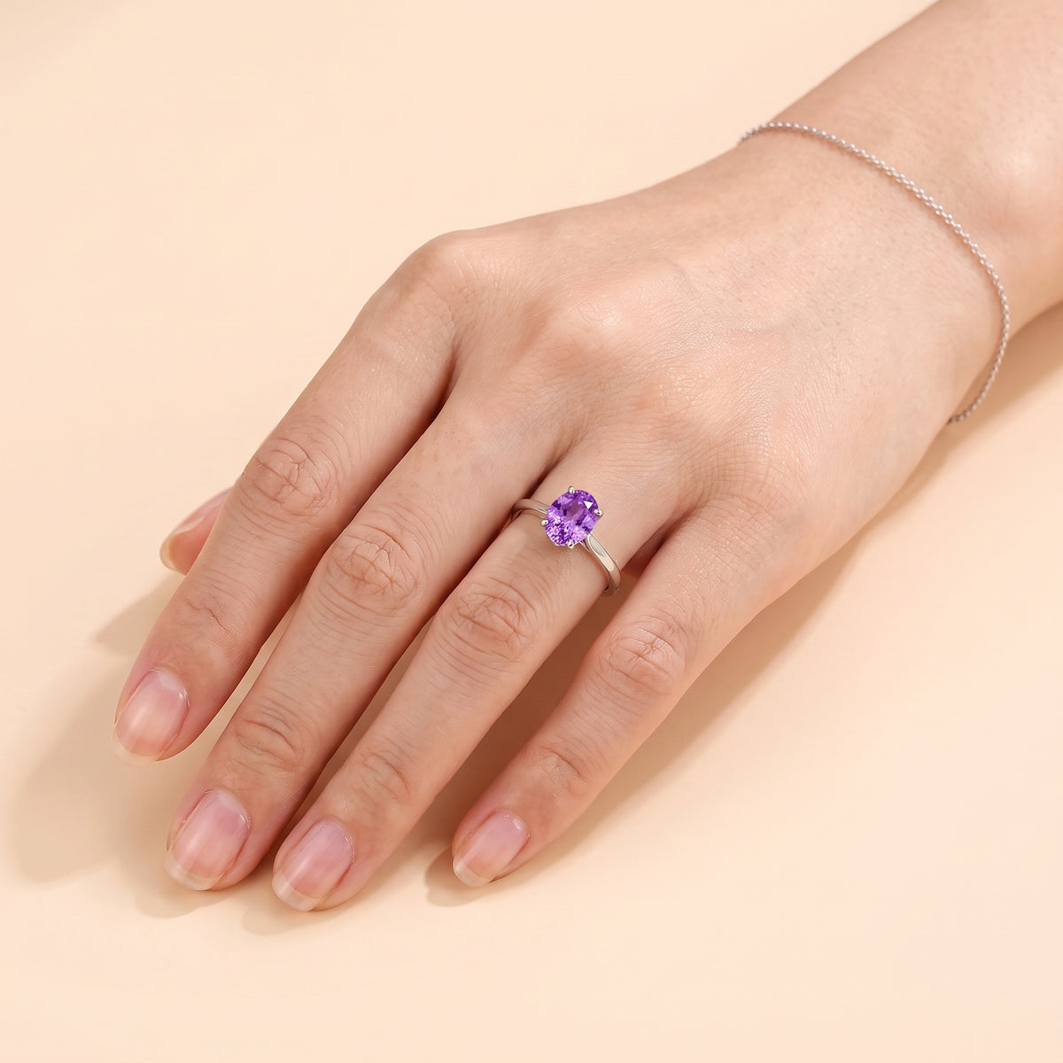 A model is wearing Lyra Oval Shape Purple Sapphire Cathedral Solitaire Ring in White Gold