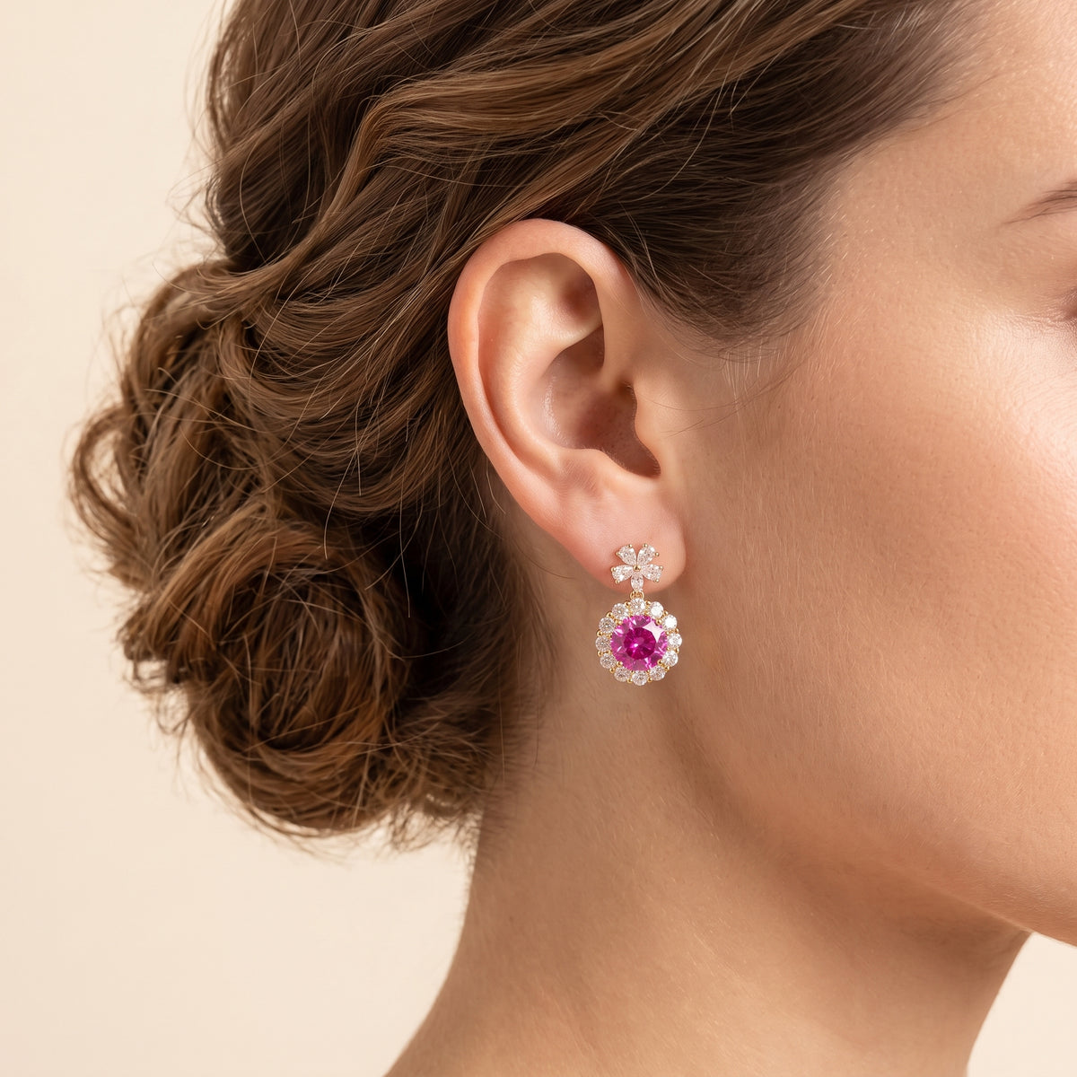 A model is wearing The Antoinette Round Vivid Pink Sapphire & Diamond Halo Pendant Earrings with Flower Bail