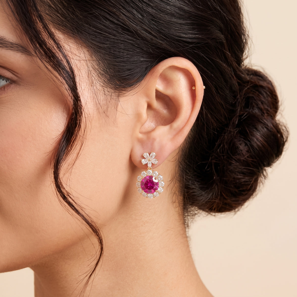 A model is wearing The Antoinette Round Vivid Pink Sapphire & Diamond Halo Pendant Earrings with Flower Bail 