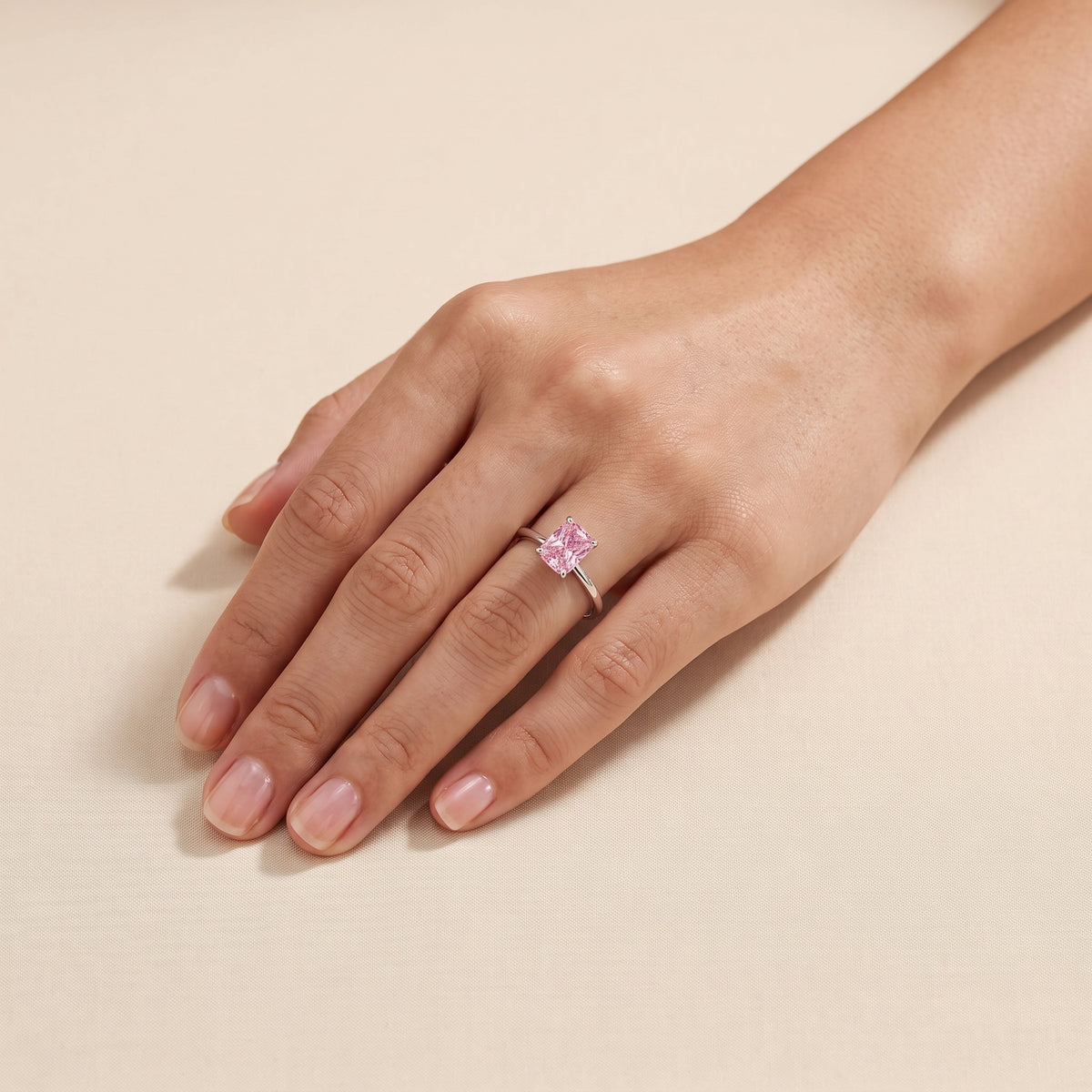 A model is wearing The Clair Radiant Shape Pastel Pink Sapphire Cathedral Solitaire Ring 
