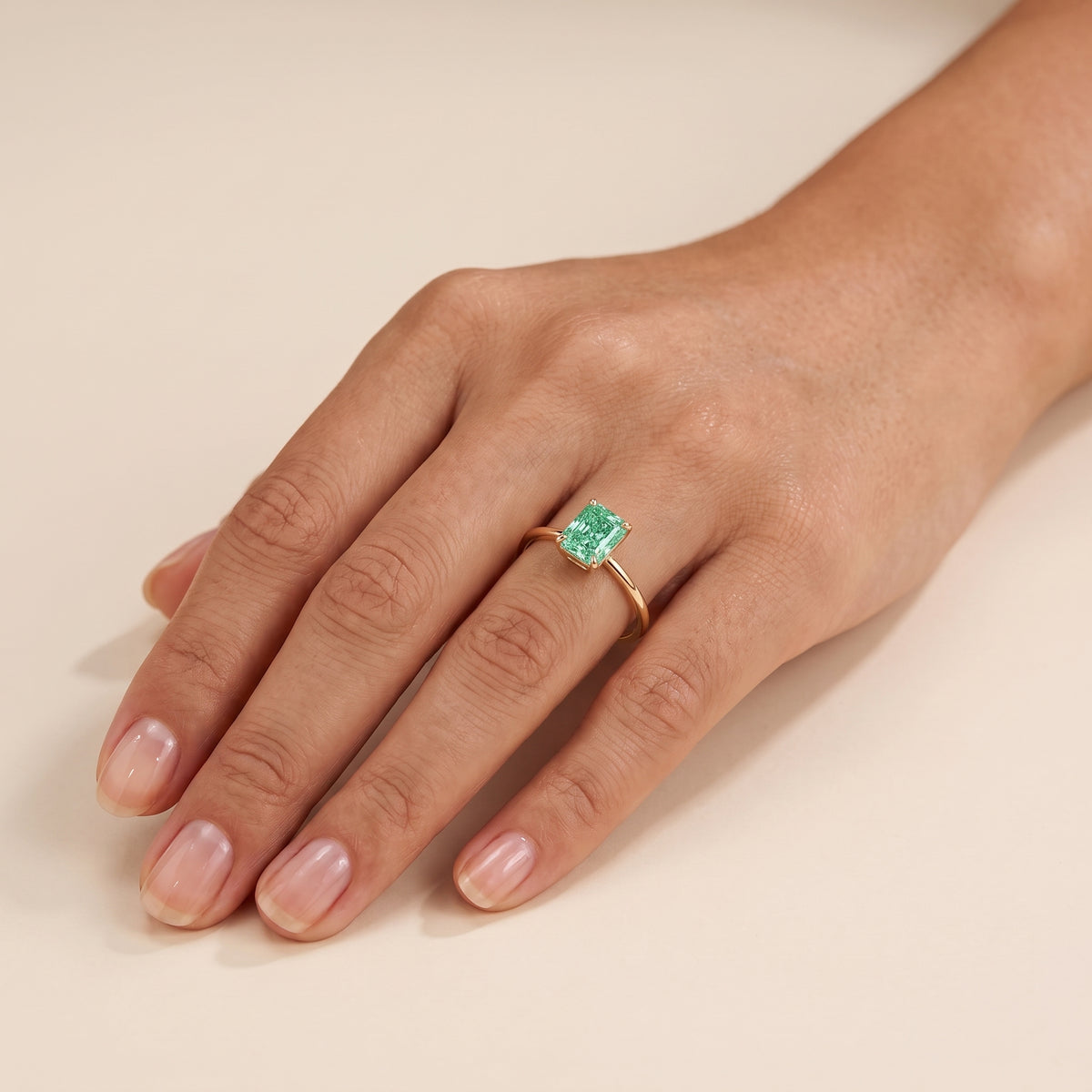 A model is wearing Clair Radiant Shape Green Sapphire Cathedral Solitaire Ring