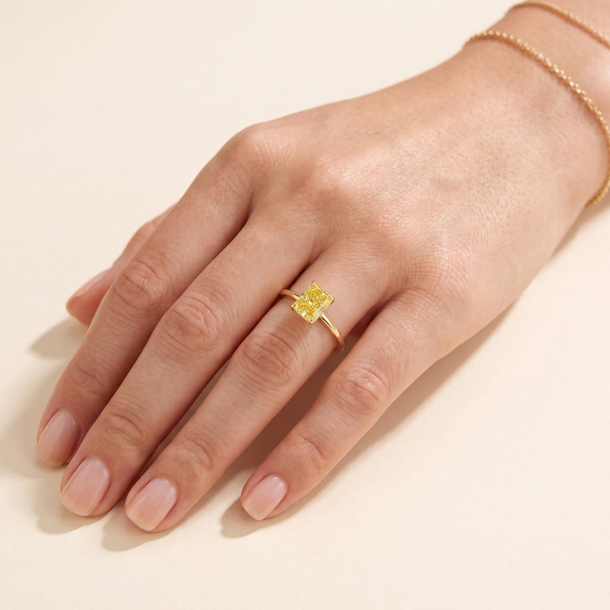 A model is wearing Clair Radiant Shape Yellow Sapphire Cathedral Solitaire Ring