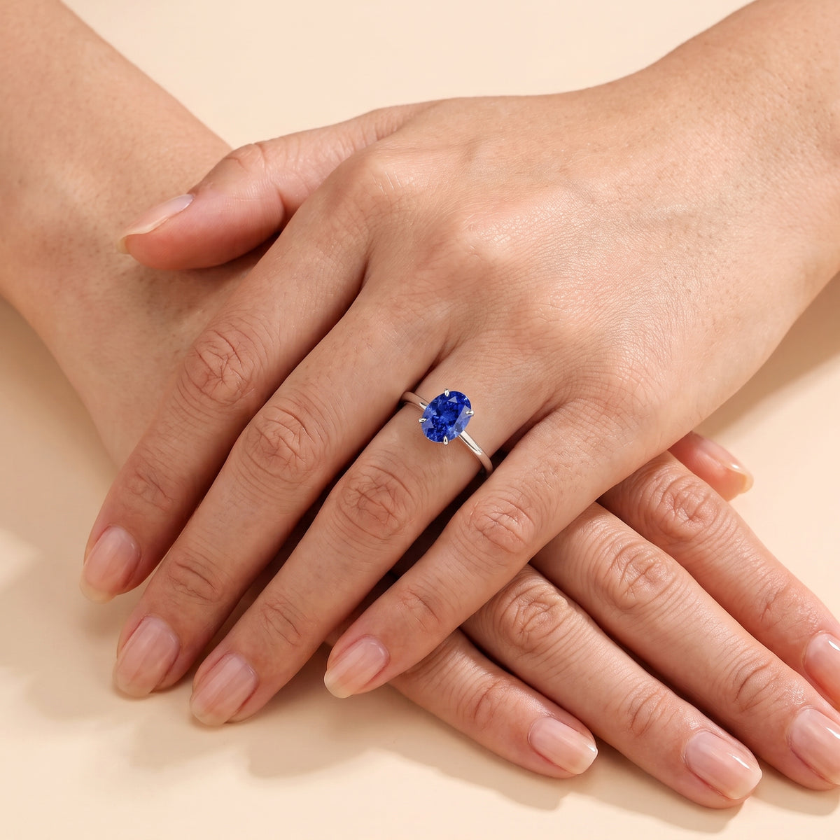 The model is wearing Lyra Oval Shape Blue Sapphire Cathedral Solitaire Ring in White Gold