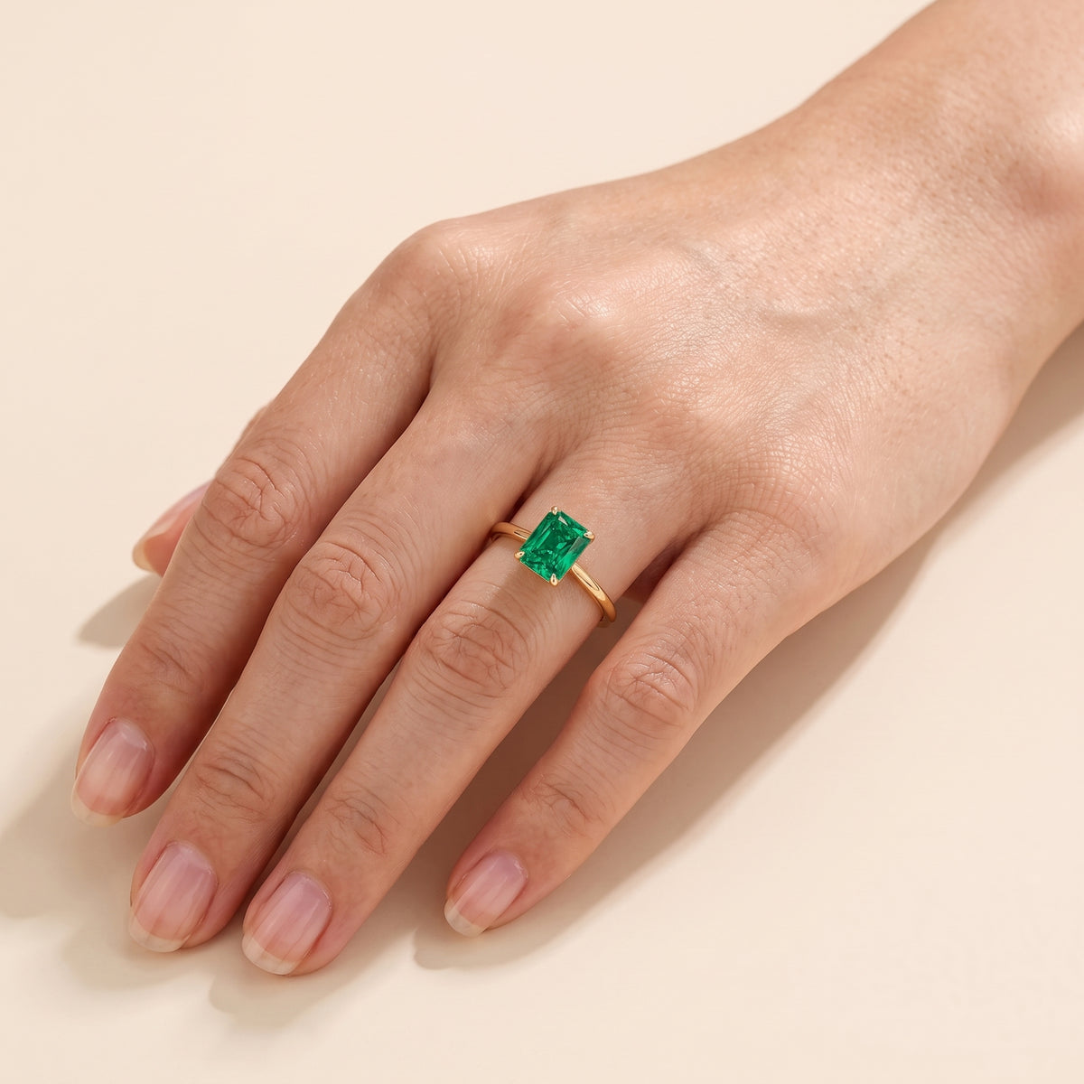 A model is wearing Clair Radiant Shape Emerald Cathedral Solitaire Ring