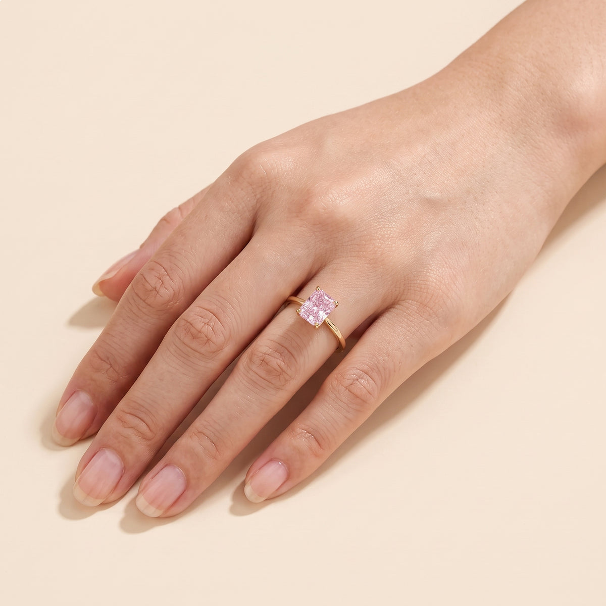 A model is wearing Clair Radiant Shape Pastel Pink Sapphire Cathedral Solitaire Ring