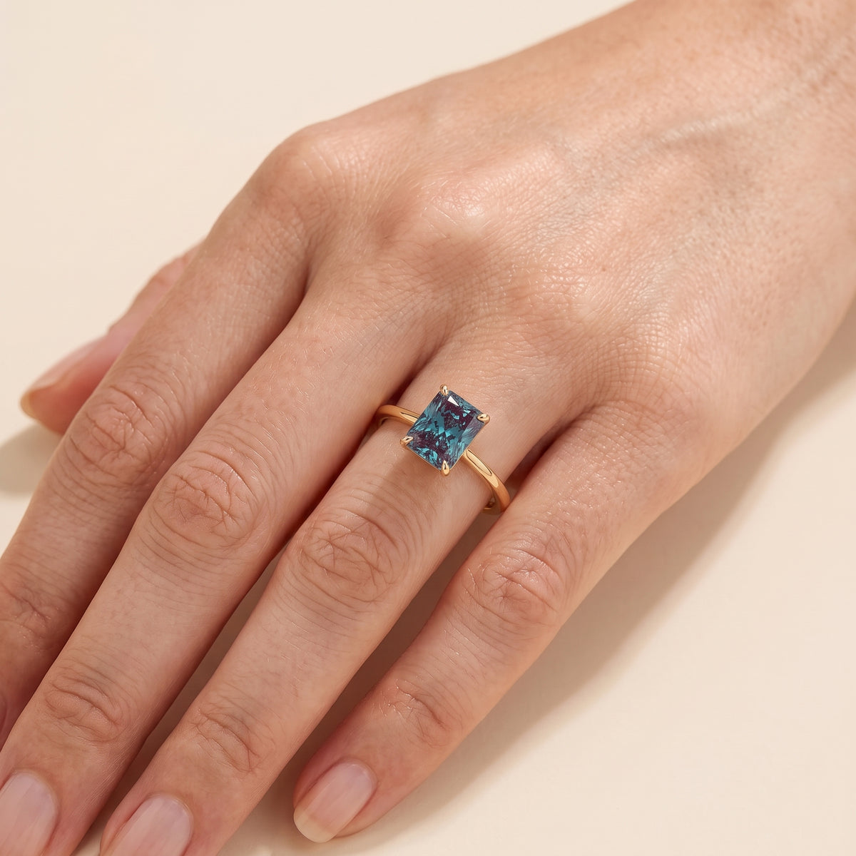 A model is wearing Clair Radiant Shape Alexandrite Cathedral Solitaire Ring
