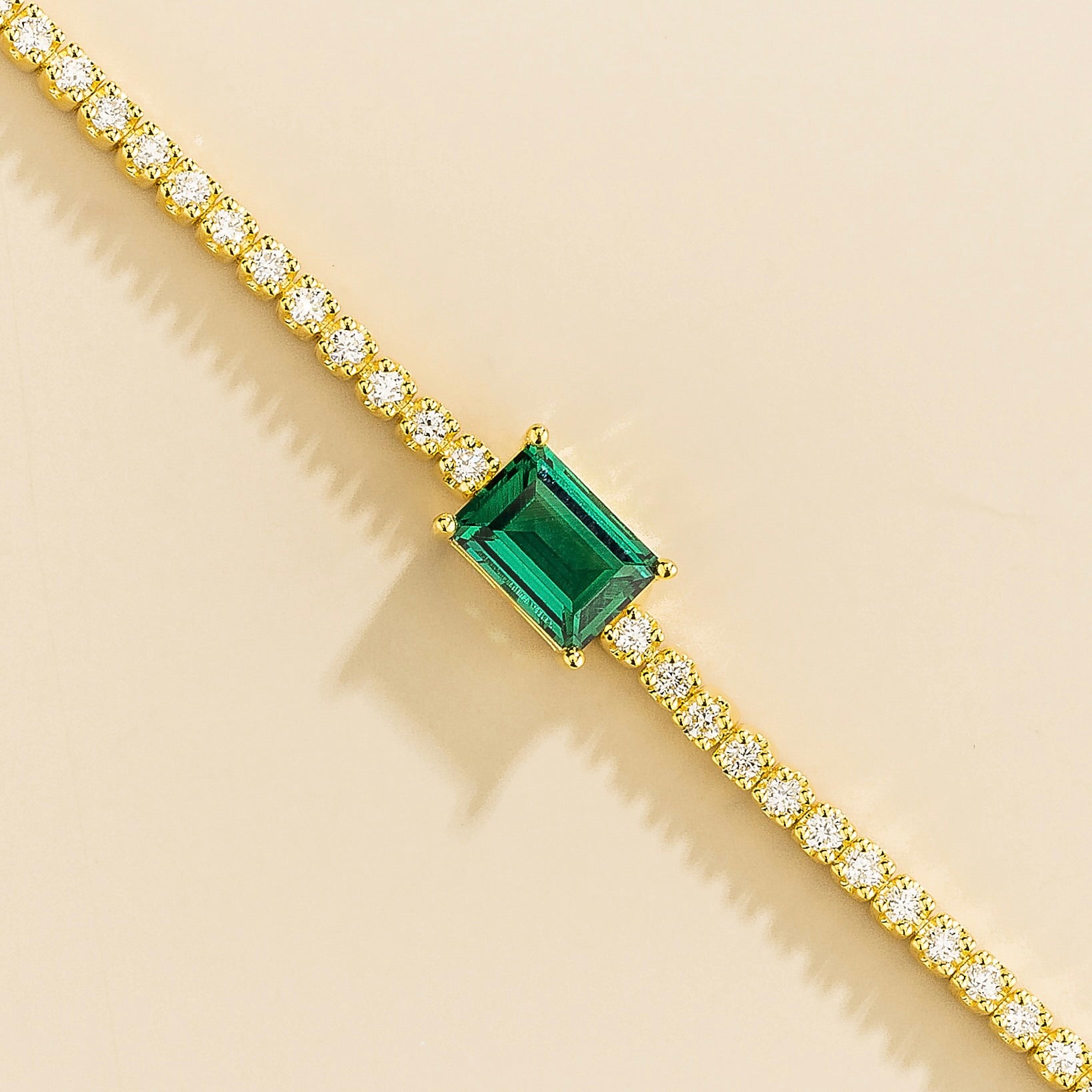 elegant gold tennis bracelet featuring emerald center stone and lab grown diamonds