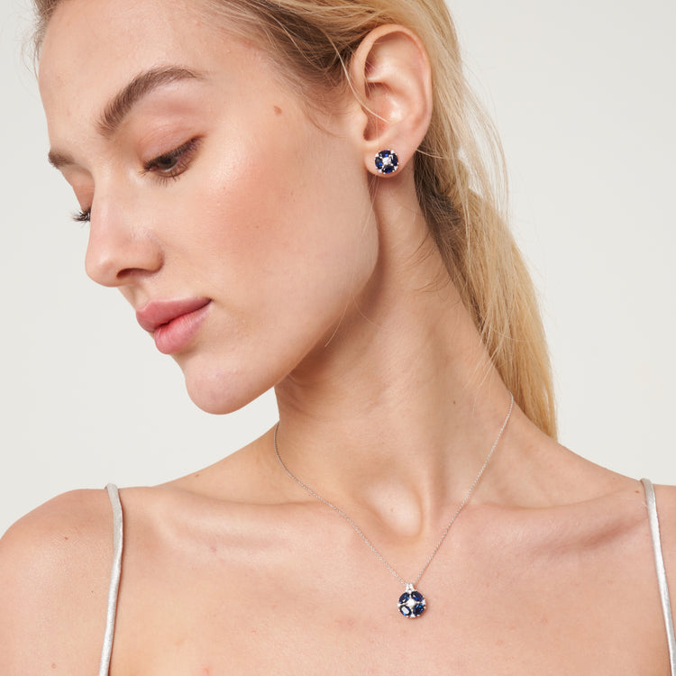 A model is wearing Pristi necklace and earrings set with lab grown diamond and oval cut blue sapphire gem stones.