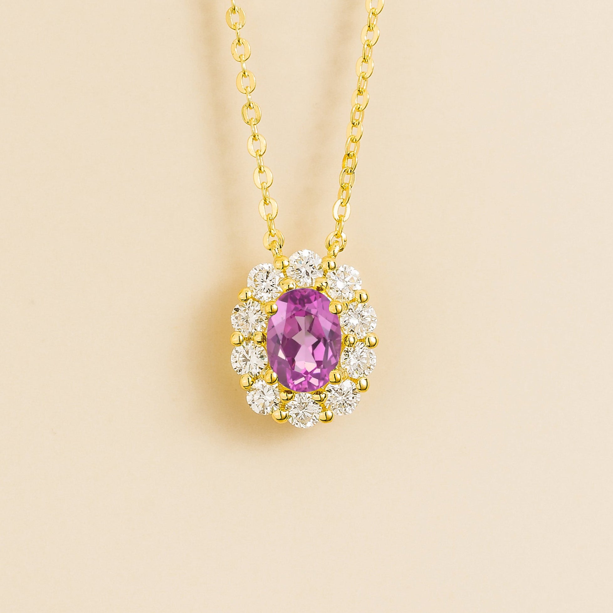 Oval pink sapphire gemstone necklace with round diamond halo on gold chain. Juvetti London Jewellery