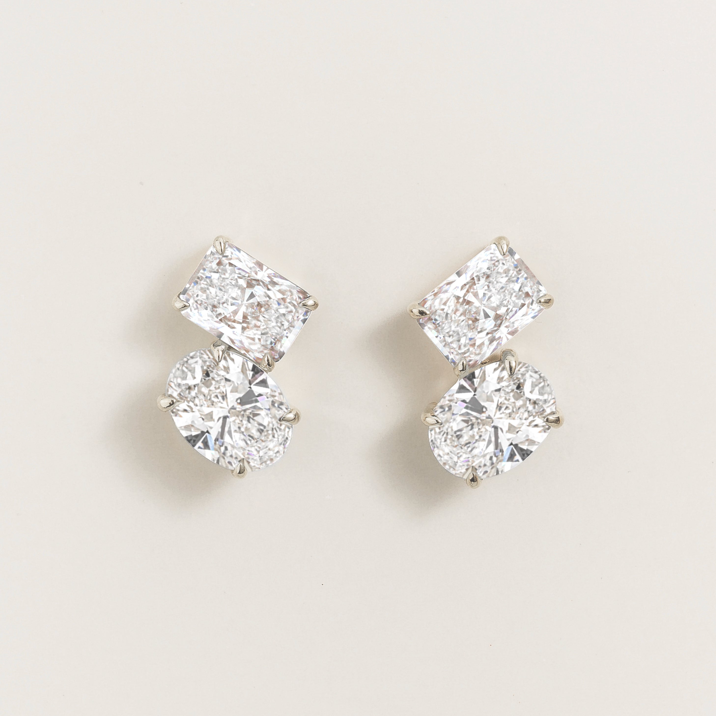 Pair of diamond toi et moi earrings on a beige background