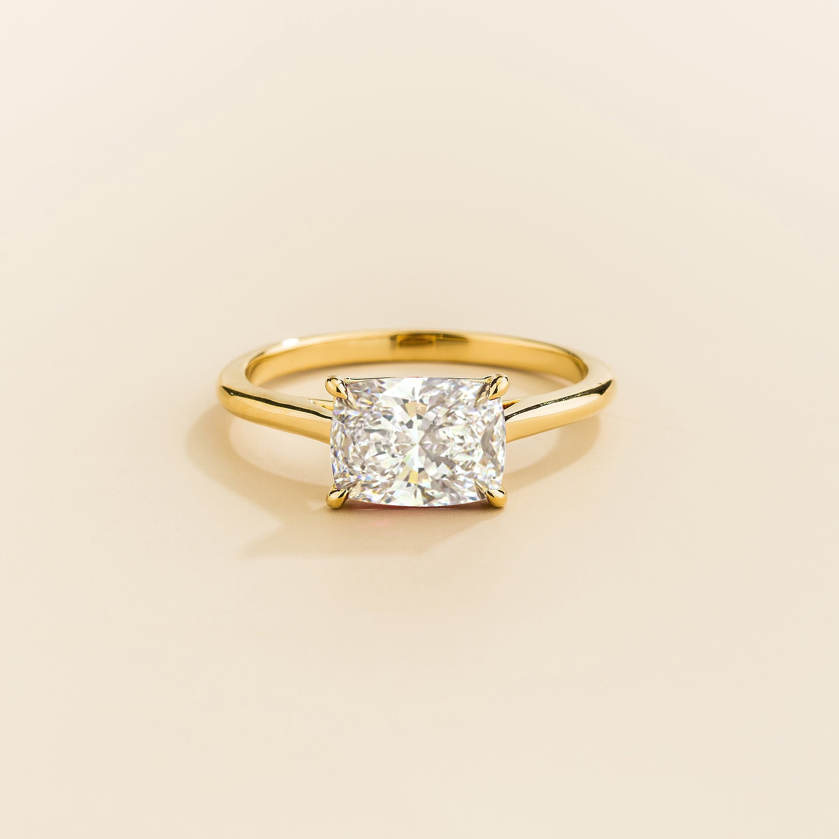 Juvetti yellow gold ring featuring a cushion-cut lab-grown diamond in an east–west setting.