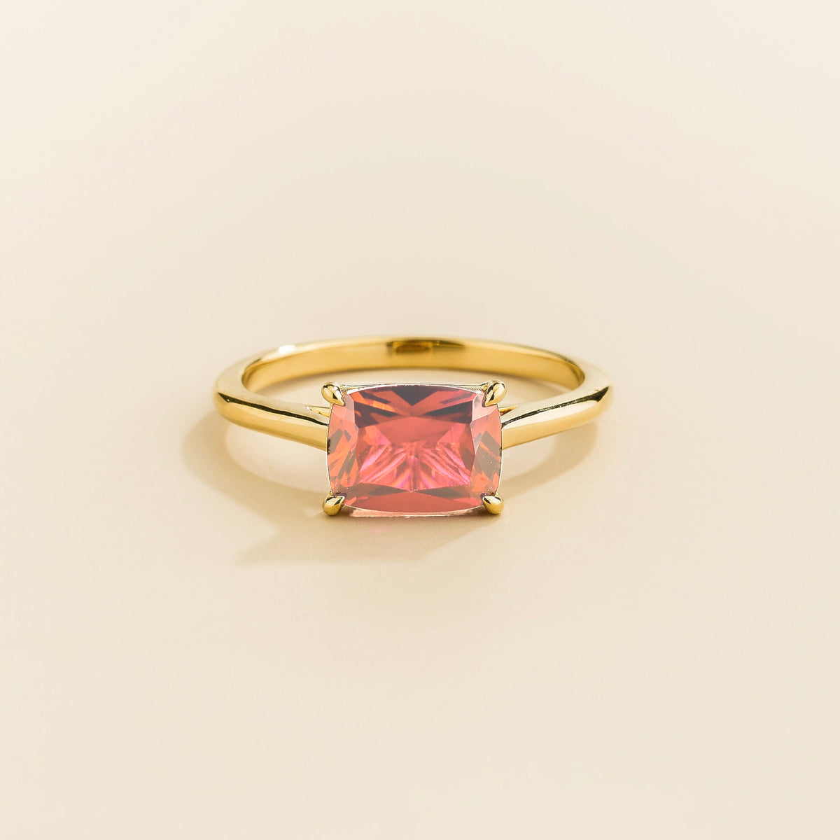 Kissen Ring in gold, set with a Padparadscha Sapphire in an east–west setting.
