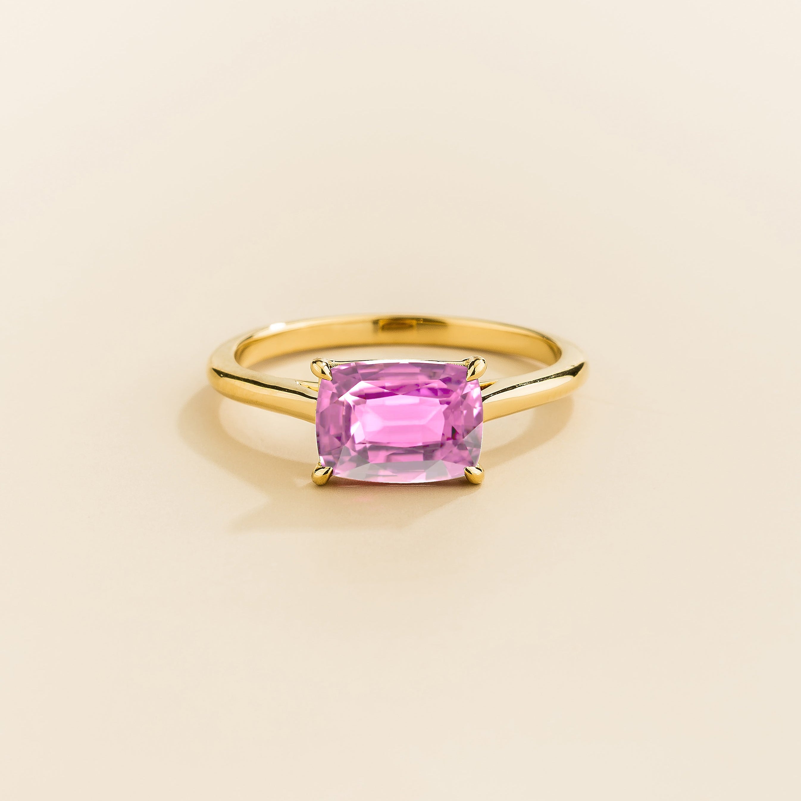Kissen Ring in gold, set with a Pink Sapphire in an east–west setting.