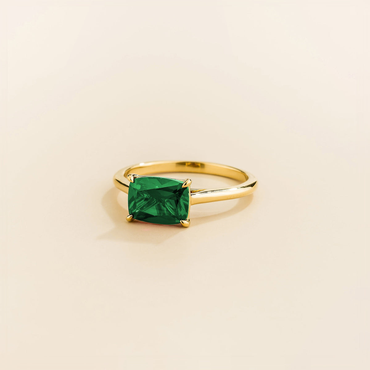 Juvetti yellow gold ring featuring a cushion-cut lab-grown emerald in an east–west setting.