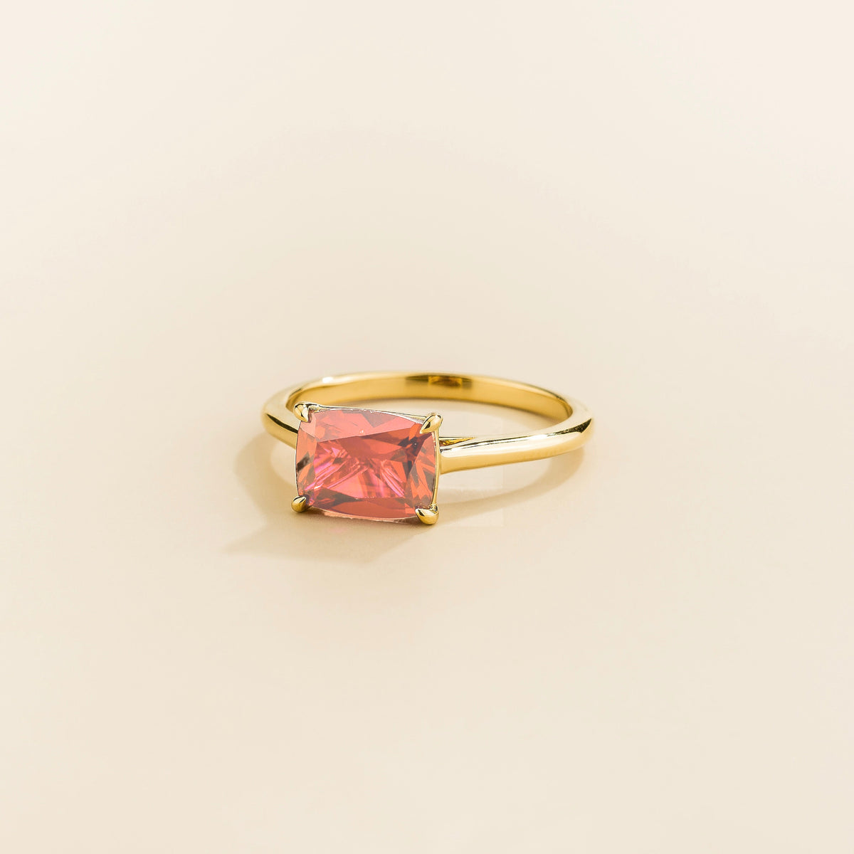 Kissen Ring in gold, set with a Padparadscha Sapphire in an east–west setting.