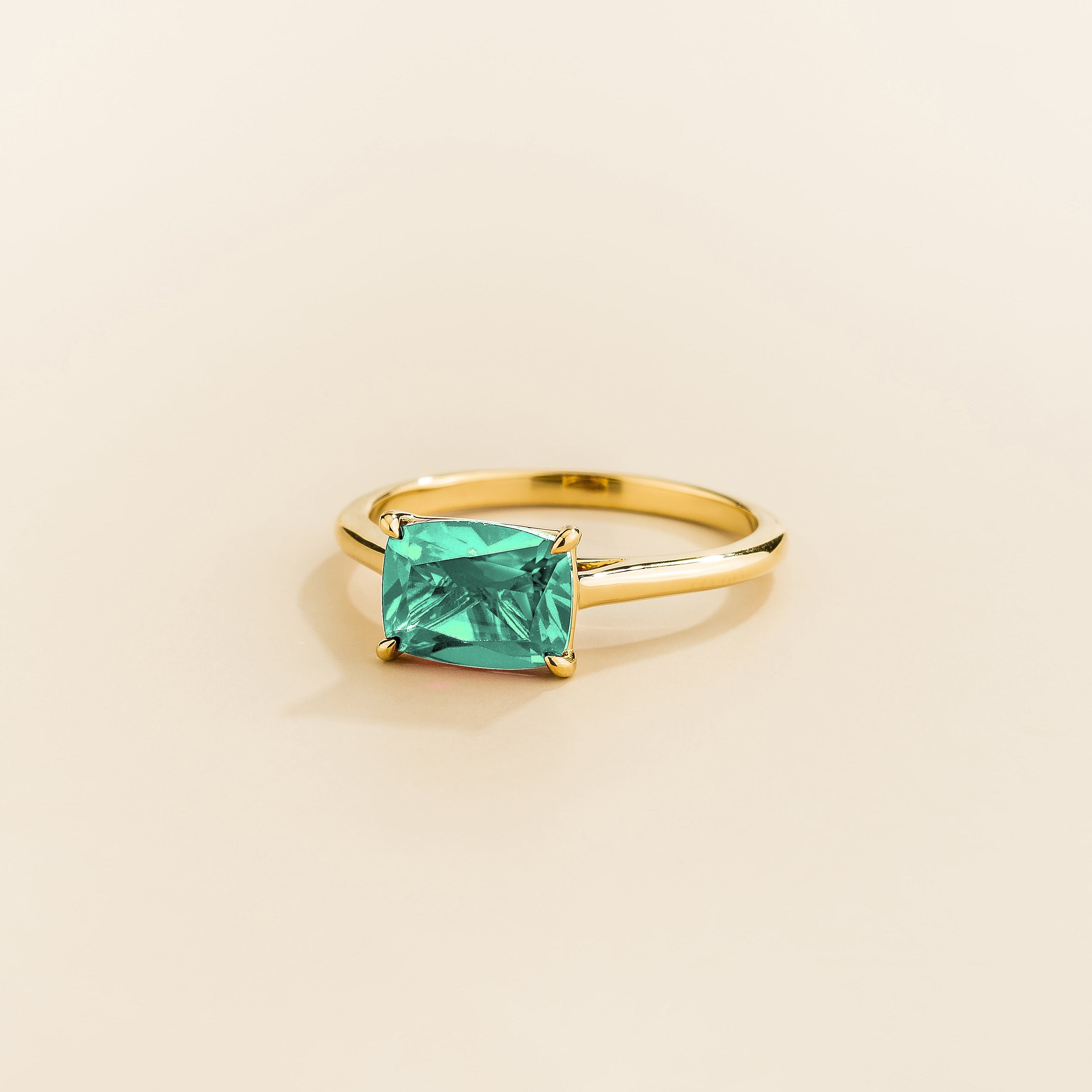 Kissen Ring in gold, set with a Paraiba Sapphire in an east–west setting.