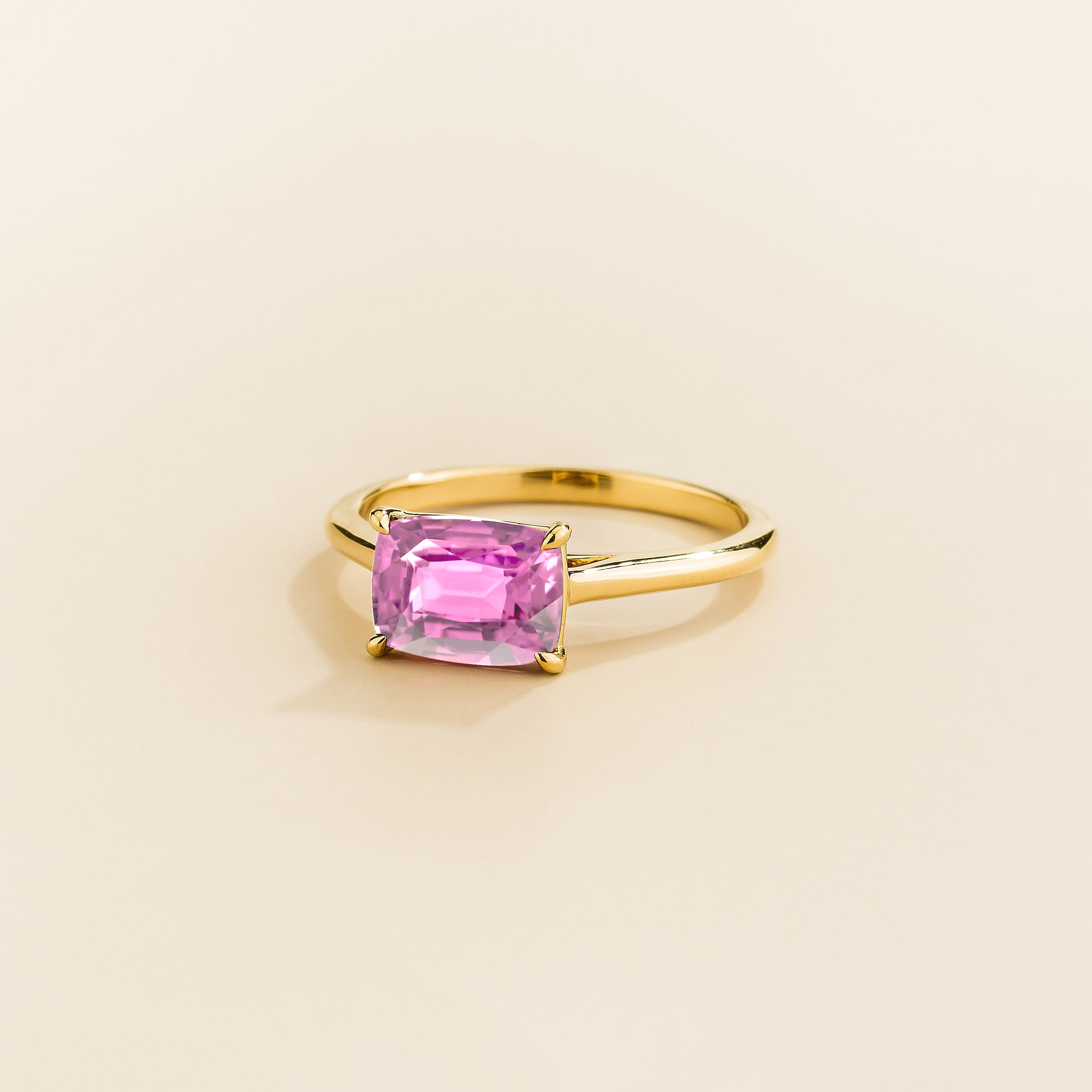 Kissen Ring in gold, set with a Pink Sapphire in an east–west setting.