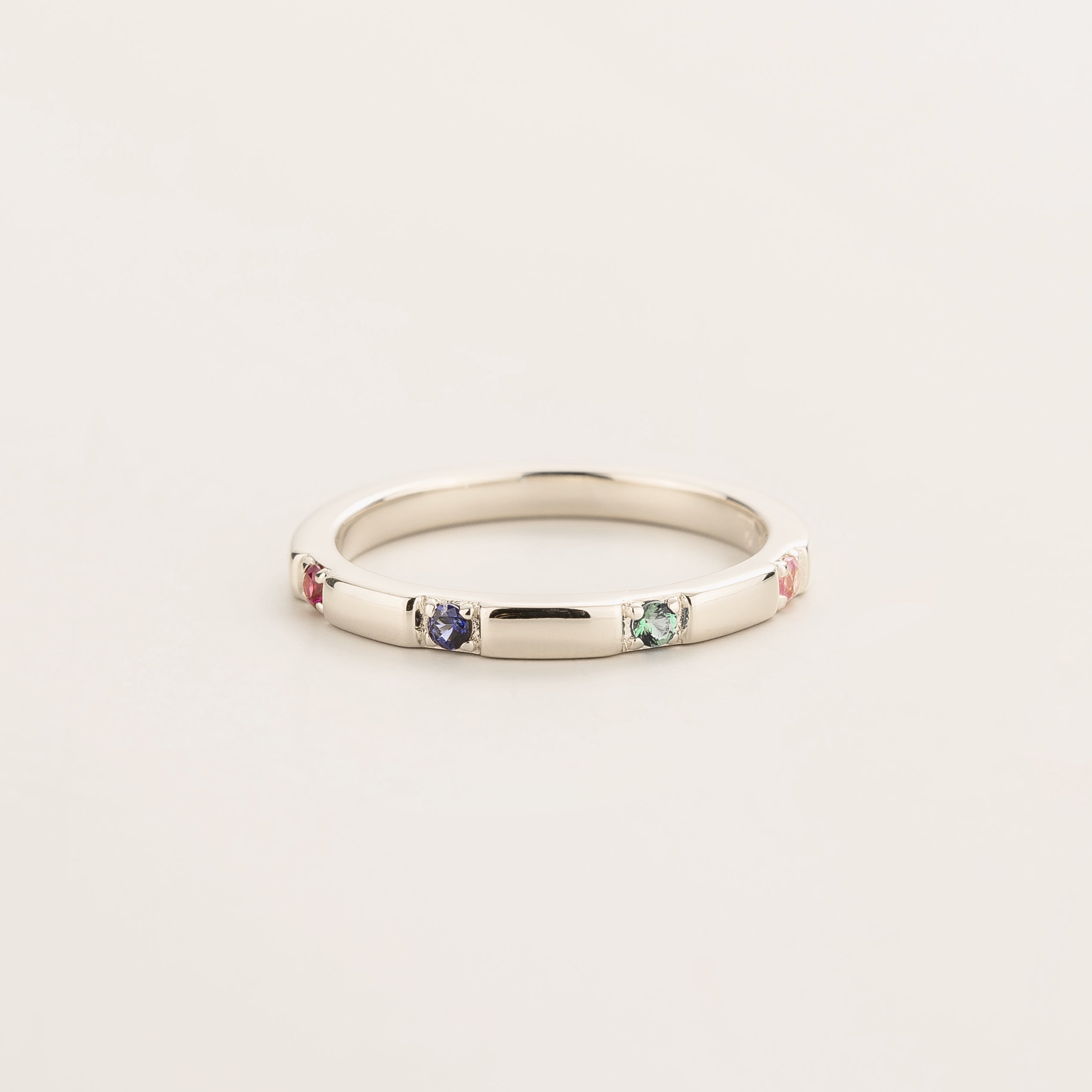 Juvetti white gold band set with round lab-grown Ruby, Blue Sapphire, Emerald and Pink Sapphire in a sleek modern design.