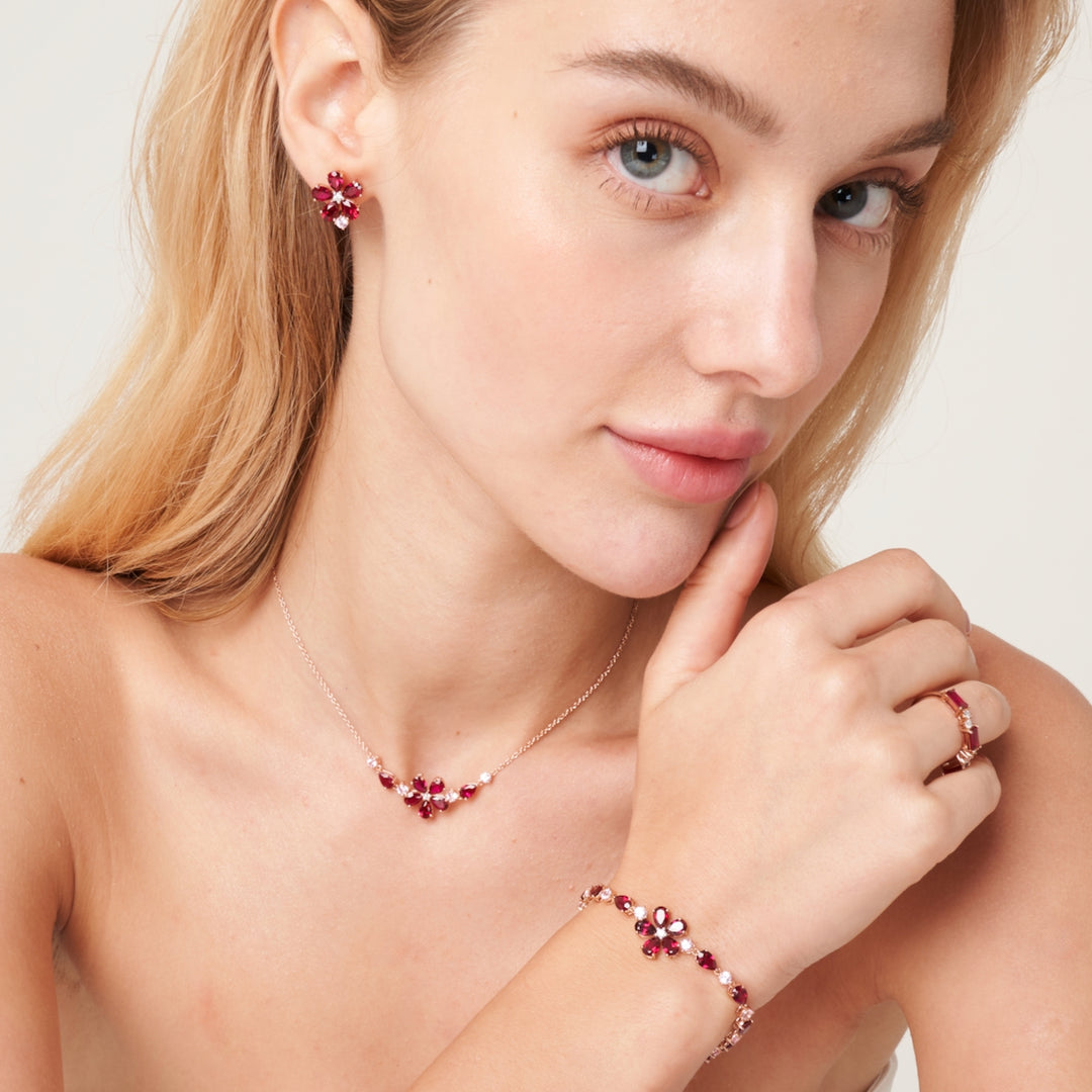 A model wearing florea flower floral set with bracelet, earrings and necklace in 18K pink gold vermeil set with lab grown diamond, ruby and pink sapphire gem stones.