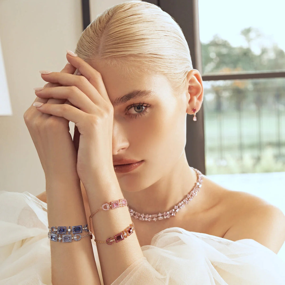 A model wearing baguette cross Ciceris bracelets made with lab grown diamond, blue sapphire, pink sapphire and ruby. She is also wearing princess and pear drop lab grown pink sapphire earrings with diamond