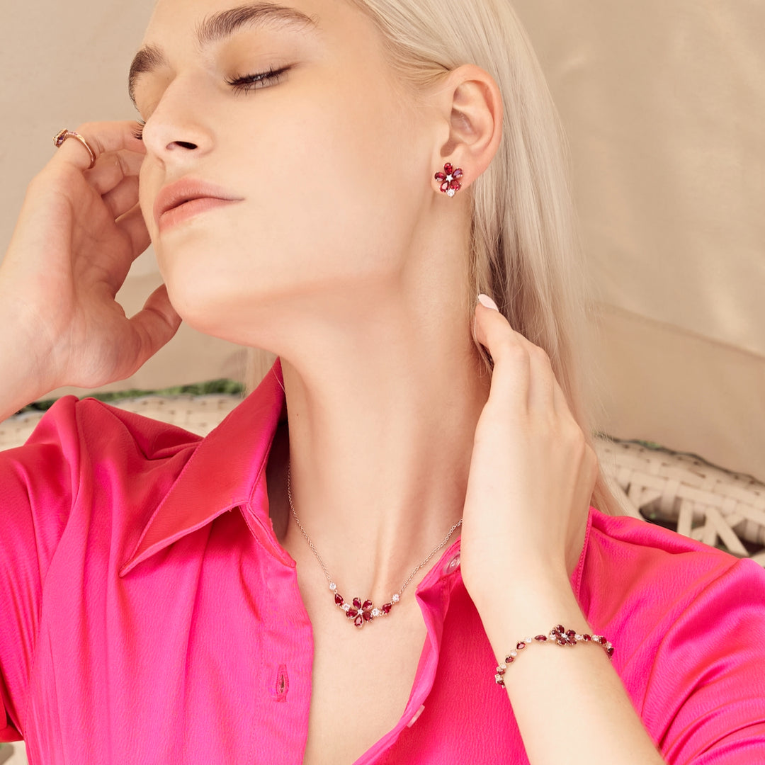 A model wearing florea flower floral set with bracelet, earrings and necklace in 18K pink gold vermeil set with lab grown diamond, ruby and pink sapphire gem stones.